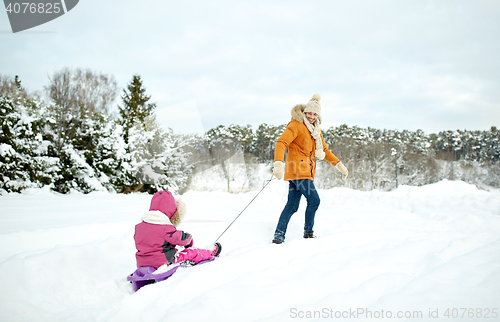 Image of happy father pulling sled with child in winter