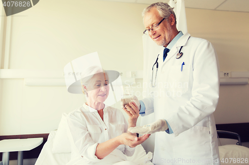 Image of doctor giving medicine to senior woman at hospital