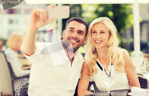 Image of happy couple taking selfie with smatphone at cafe