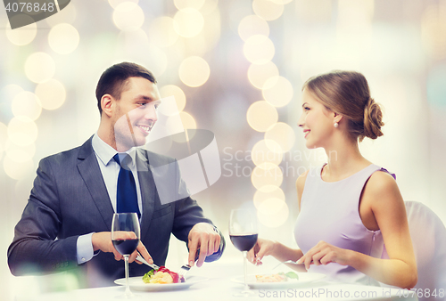 Image of smiling couple eating main course at restaurant