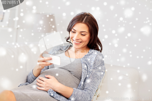 Image of happy pregnant woman with smartphone at home