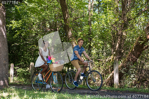 Image of Young multiethnic couple having a bike ride in nature
