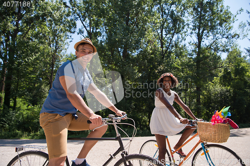 Image of Young multiethnic couple having a bike ride in nature