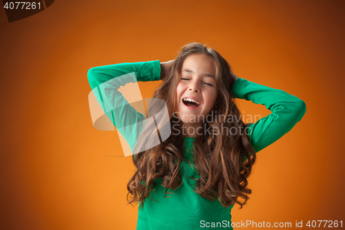 Image of The cute cheerful little girl on orange background