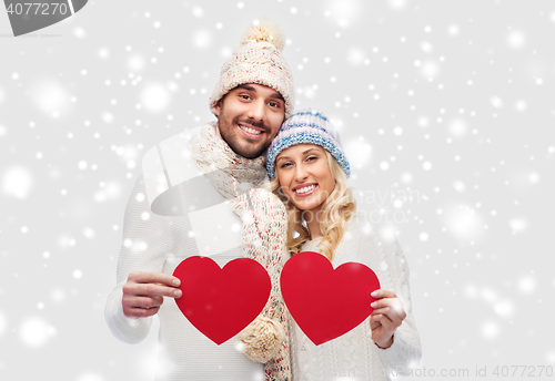 Image of smiling couple in winter clothes with red hearts