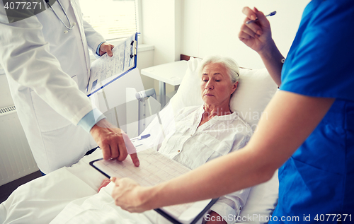 Image of doctor and nurse visiting senior woman at hospital