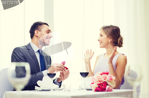 Image of man proposing to his girlfriend at restaurant