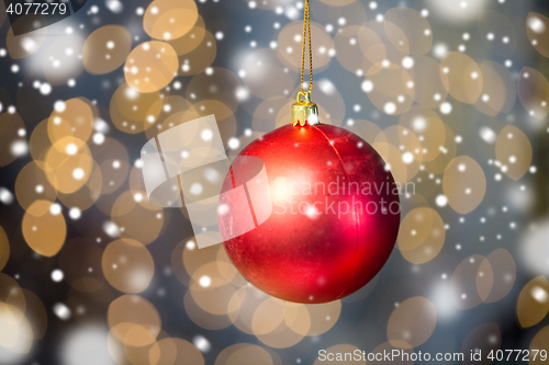 Image of close up of red christmas ball over golden lights