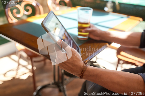 Image of close up of man with tablet pc and beer at pub