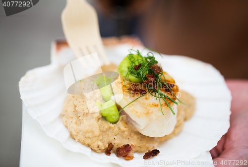 Image of close up of scallop snack with garnish on seashell