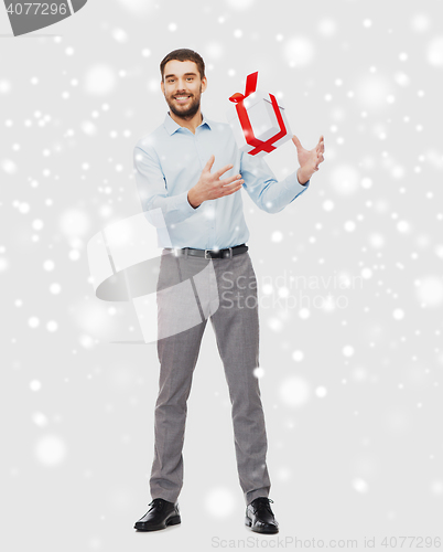 Image of happy young man with christmas gift box over snow