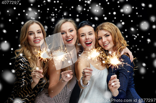 Image of happy young women with sparklers over snow