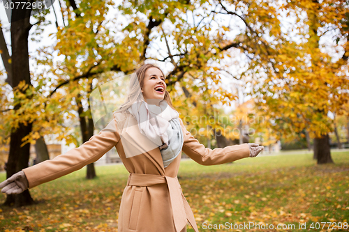 Image of beautiful happy young woman walking in autumn park