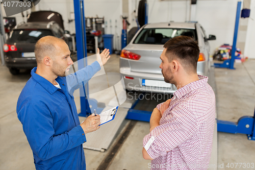 Image of auto mechanic with clipboard and man at car shop