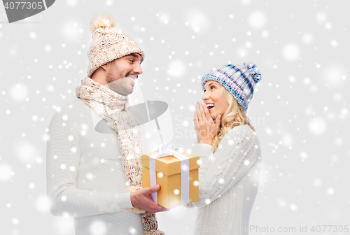 Image of smiling couple in winter clothes with gift box