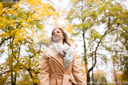 Image of beautiful happy young woman walking in autumn park