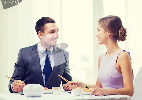 Image of smiling couple eating sushi at restaurant