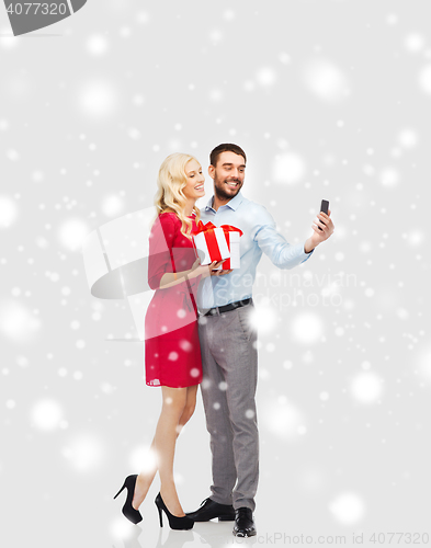 Image of happy couple with smartphone and christmas gifts