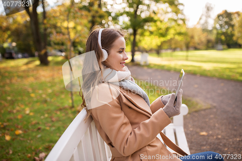 Image of woman with tablet pc and headphones in autumn park