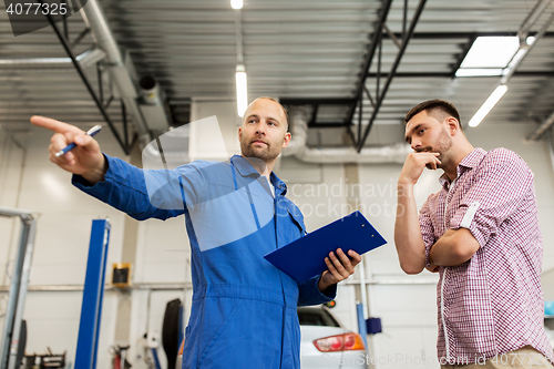 Image of auto mechanic with clipboard and man at car shop