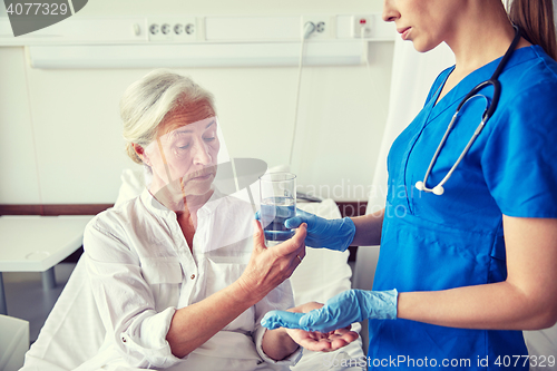 Image of nurse giving medicine to senior woman at hospital