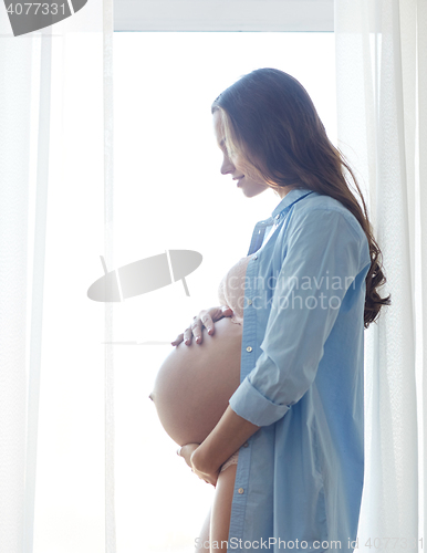 Image of happy pregnant woman with big bare tummy at home