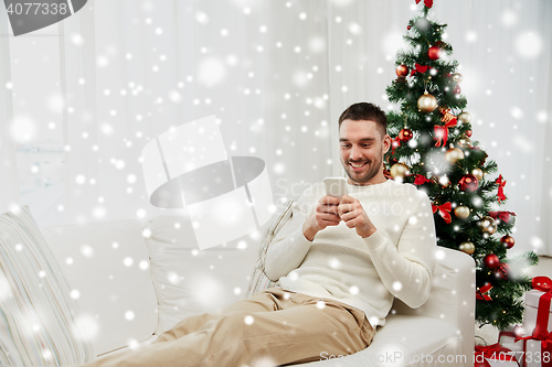Image of smiling man with smartphone at home for christmas