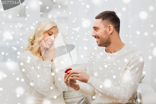 Image of happy man giving engagement ring to woman at home