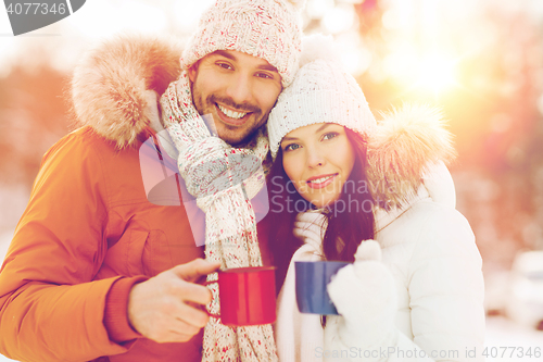 Image of happy couple with tea cups over winter landscape