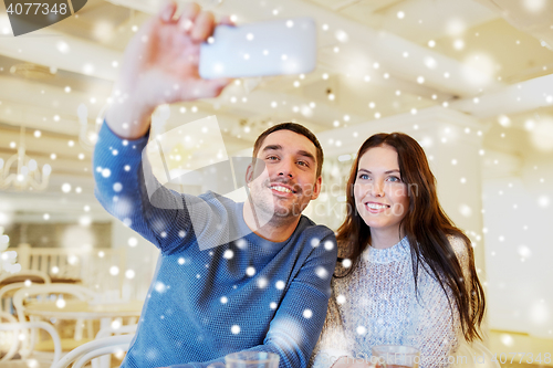 Image of couple taking smartphone selfie at cafe restaurant