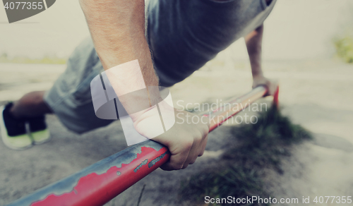 Image of young man exercising on horizontal bar outdoors