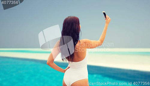 Image of young woman taking selfie with smartphone