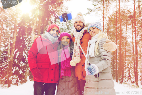 Image of smiling friends with smartphone in winter forest