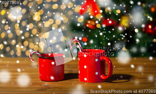 Image of christmas candy canes and cups on wooden table