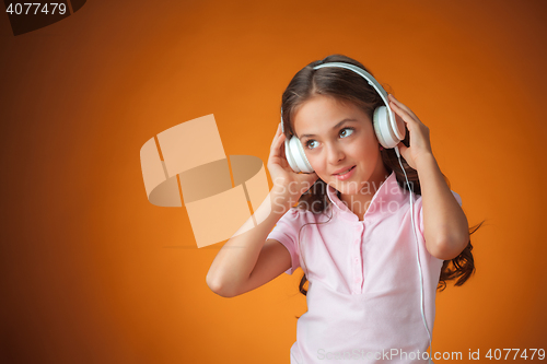 Image of The cute cheerful little girl on orange background