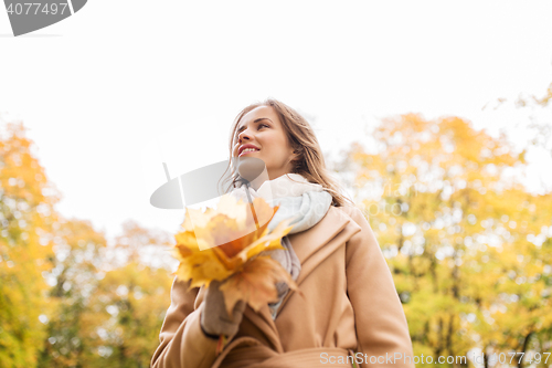 Image of beautiful woman with maple leaves in autumn park