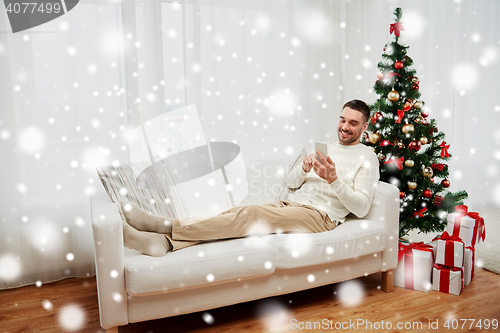 Image of smiling man with smartphone at home for christmas