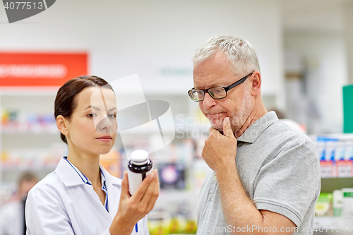 Image of pharmacist showing drug to senior man at pharmacy