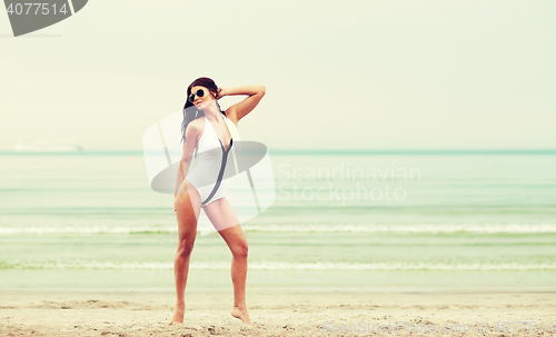 Image of young woman in swimsuit posing on beach