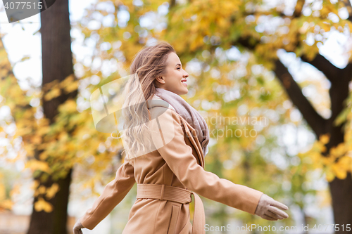 Image of beautiful happy young woman walking in autumn park