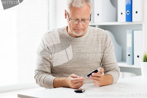 Image of senior man with glucometer checking blood sugar