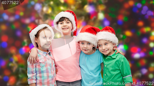 Image of happy little children in santa hats hugging