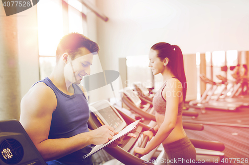 Image of happy woman with trainer on treadmill in gym