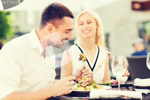 Image of happy couple eating dinner at restaurant terrace