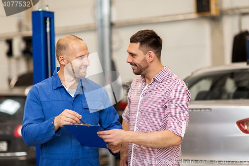 Image of auto mechanic with clipboard and man at car shop
