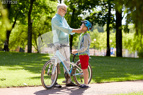 Image of grandfather and boy with bicycle at summer park