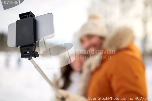 Image of happy couple taking selfie by smartphone in winter