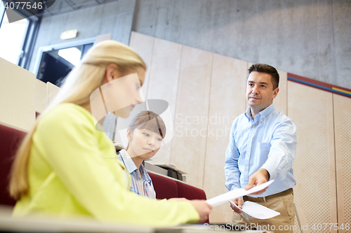 Image of teacher giving exam tests to students at lecture