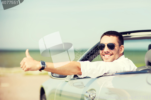 Image of happy man driving car and showing thumbs up