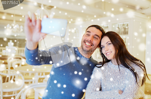 Image of couple taking smartphone selfie at cafe restaurant